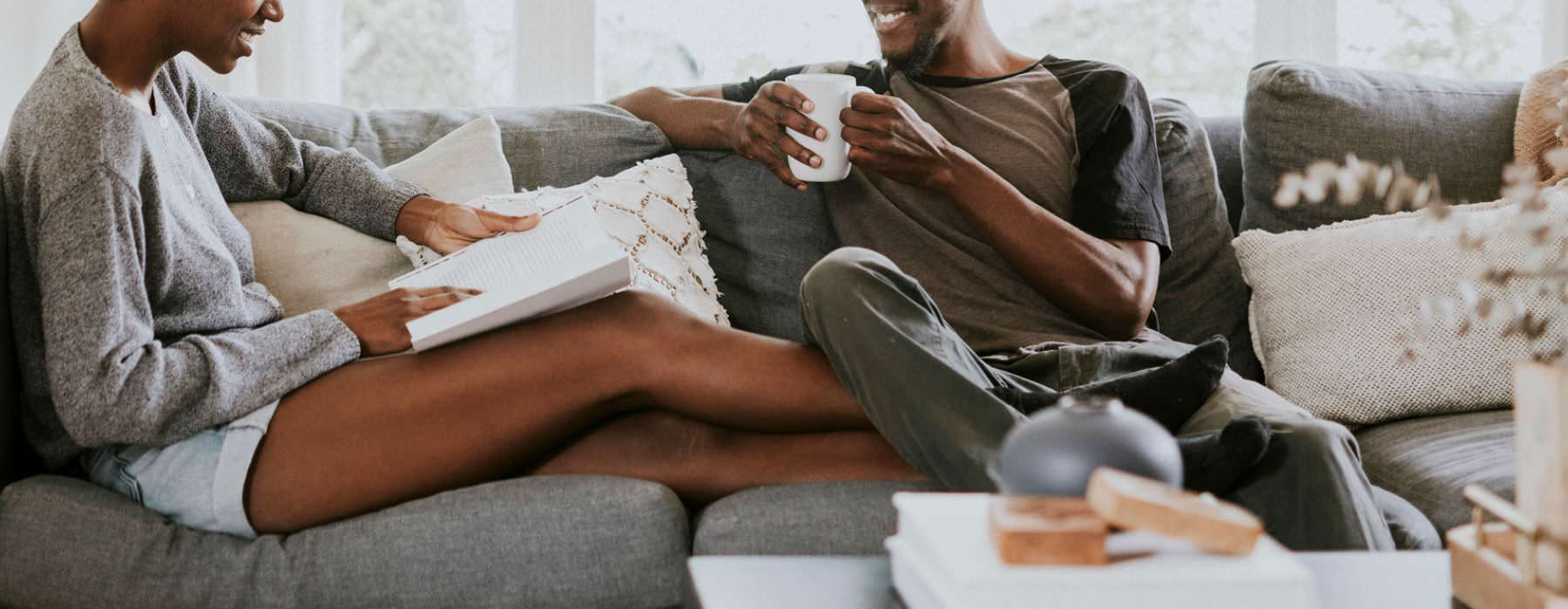Lifestyle photo of young couple sit on their living room couch reading and drinking coffee
