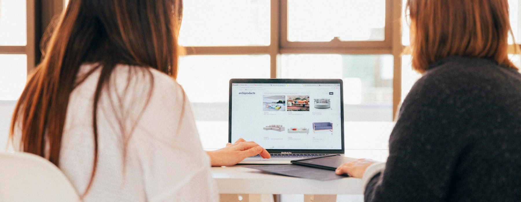 two women work on a laptop at the office
