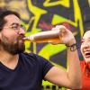 man and woman drink soda in front of a city mural